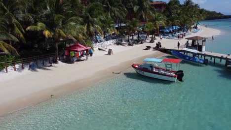 Boats-tied-up-on-white-sandy-beach-of-charming-beach-resort-on-Roatan