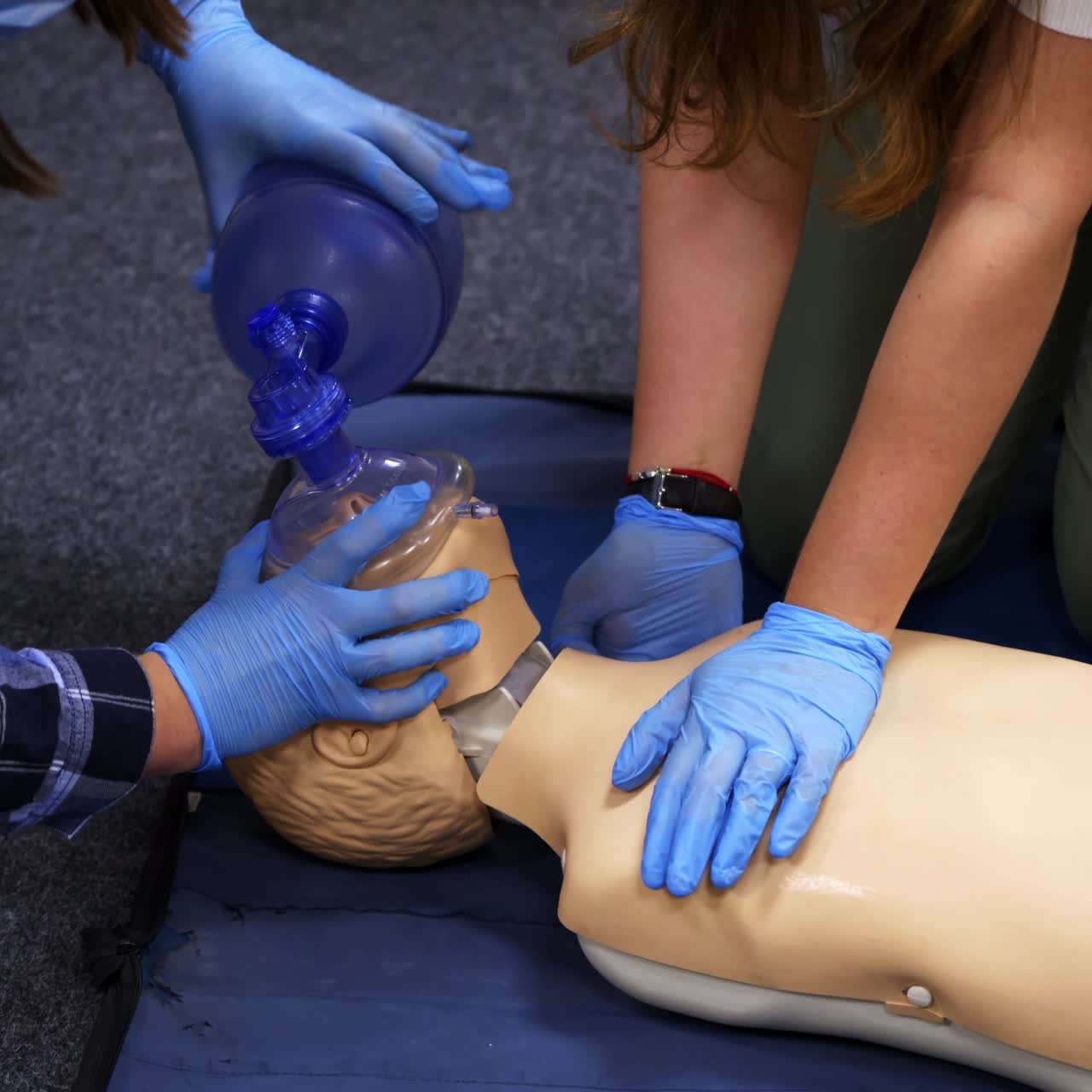 Training for emergency aid course. First aid cpr resuscitation training on manikin. Women in sterile gloves breathing apparatus on a dummy.