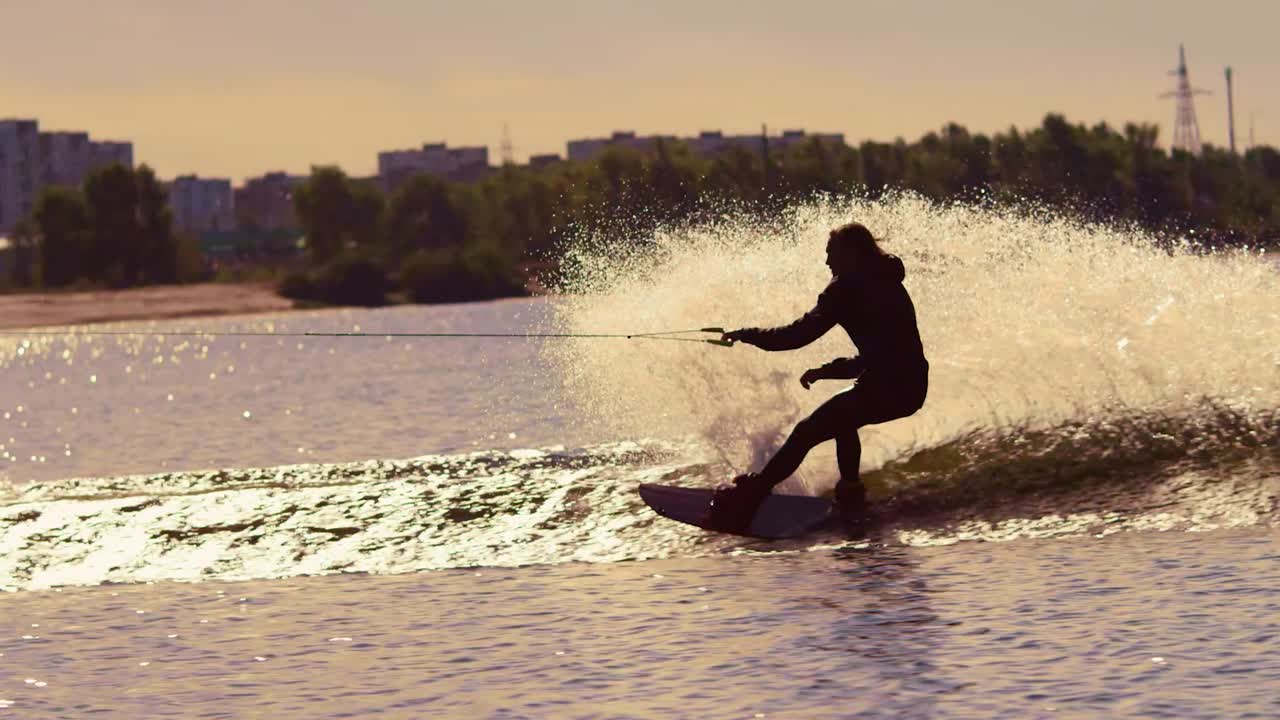 hombre haciendo wakeboard en el agua al atardecer. wakeboarder haciendo trucos