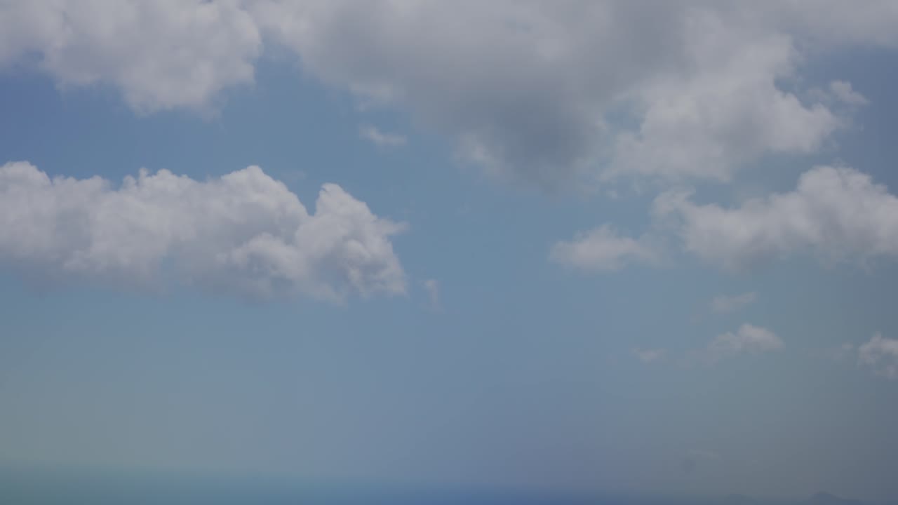 View of large clouds moving above and below outside of chromatic airplane window with water drop on it as plane tilts, Santorini, Greece, Europe