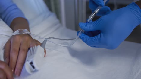 Mixed-race-female-patient-lying-in-bed-wearing-fingertip-pulse-oximeter-getting-injection