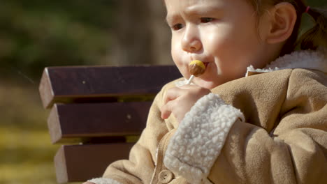 Young-girl-enjoys-lollipop-on-bench-in-Yangjae-Park,-Seoul,-South-Korea