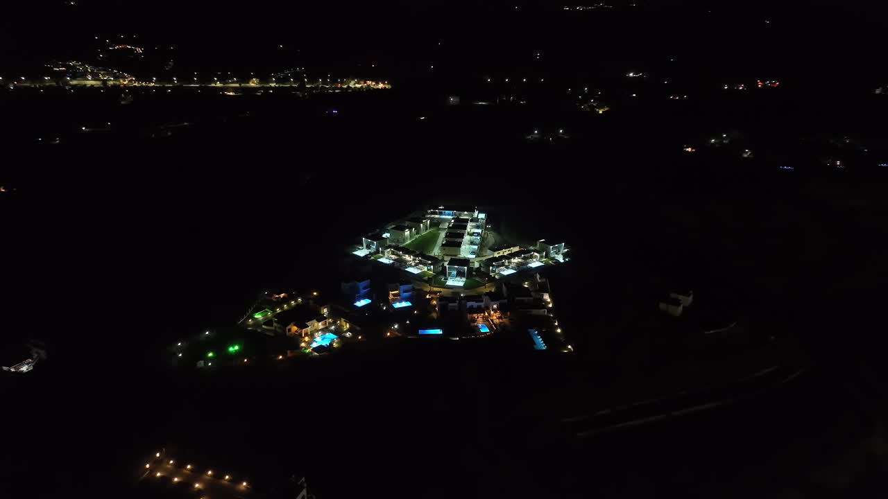 Wide drone shot flying around a illuminated vacation town, during nighttime