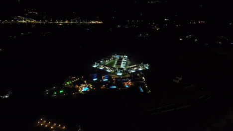 wide drone shot flying around a illuminated vacation town, during nighttime