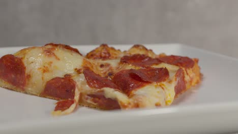 a close-up of pizza slices on a plate indoors reveals the rich, melted cheese and savory toppings