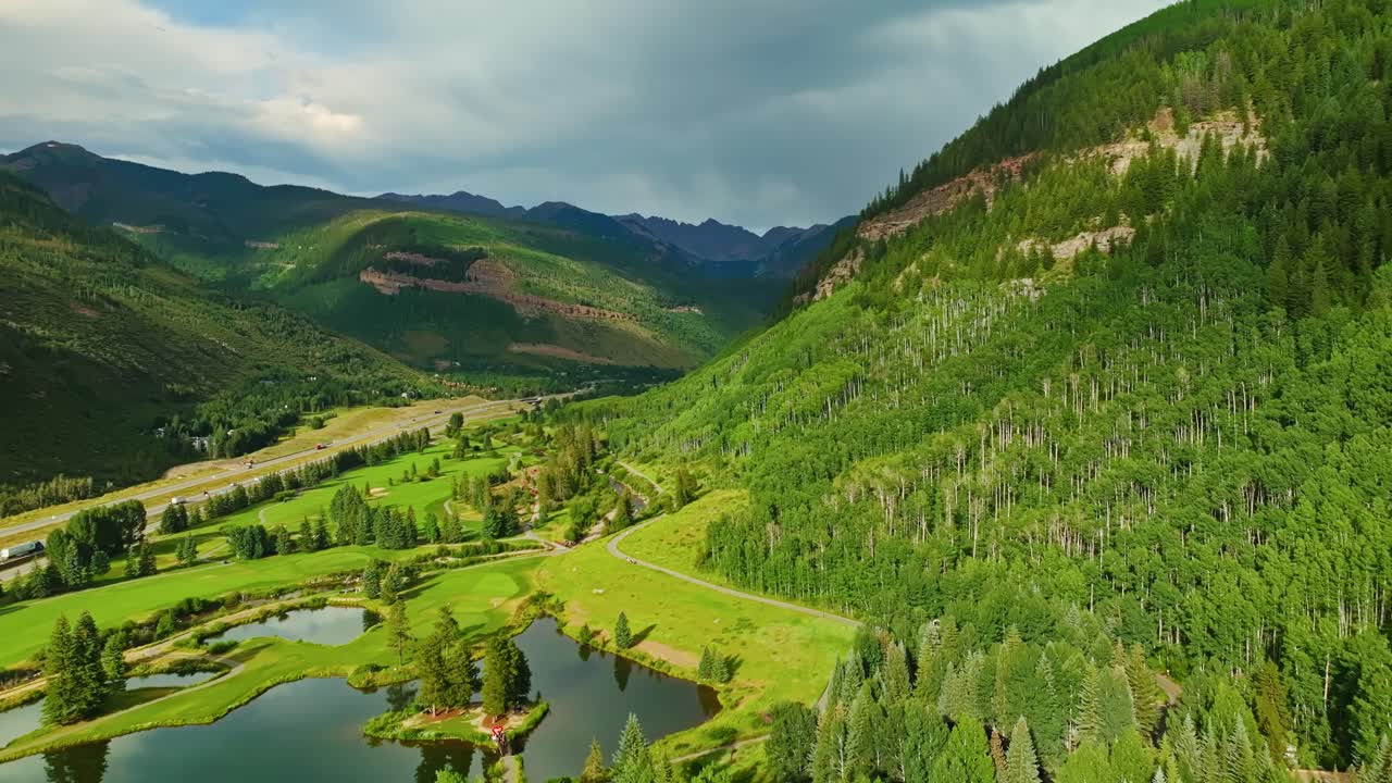 Tight aerial of lush green Vail hillside with dense vegetation and patterns in summer light, golden hour glow across golf course
