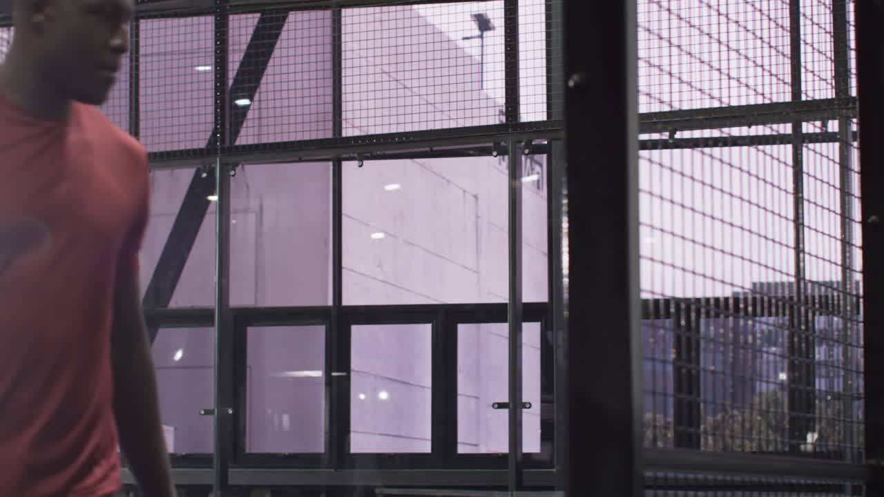 Athlete in red shirt resting on bench after intense padel tennis match, at indoor court