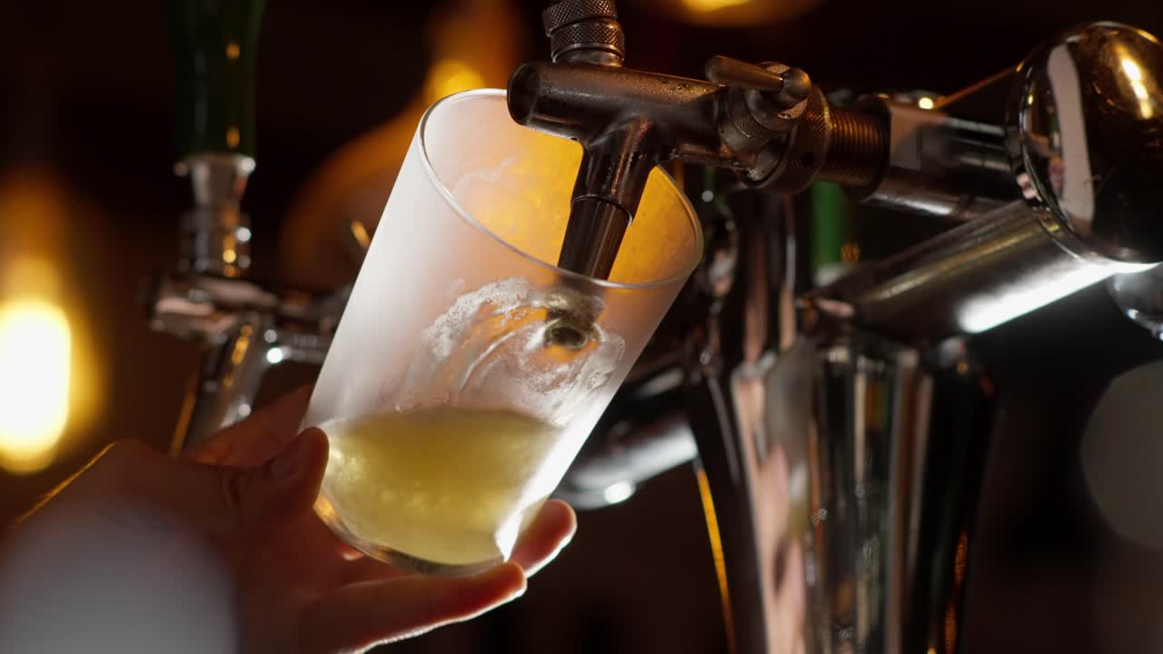 Close-up of golden beer flowing smoothly from a beer tap into a glass, creating frothy foam