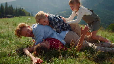 Die-Familie-Stapelte-Sich-Auf-Einem-Grünen-Grashügel-Aus-Nächster-Nähe.-Glückliche-Eltern-Spielen.