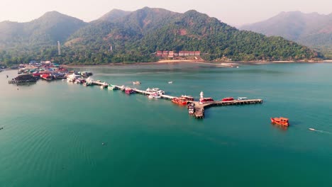 aerial pullback ascend from pier and docks along koh chang’s coastline, turquoise waters and green islands in thailand at early morning