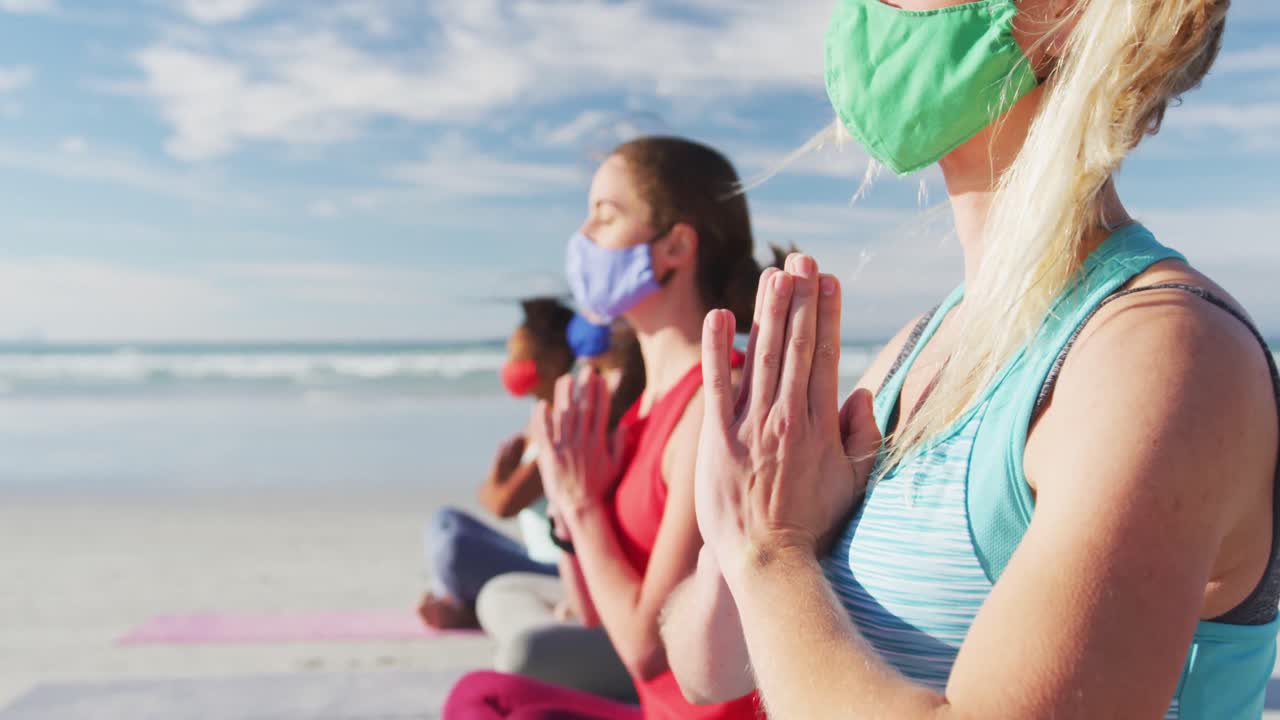 해변 에서 명상 하는 얼굴 마스크 를 착용 한 다양한 여성 친구 들 의 그룹