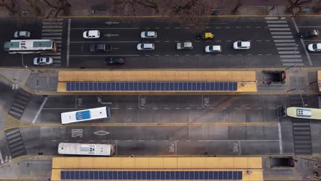 ascending aerial birds eye of busy traffic on multilane road and bus stop in capital of argentina