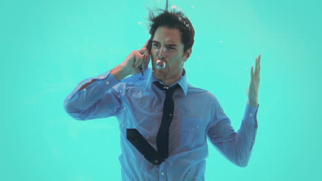 un hombre de negocios bajo el agua hablando en su teléfono inteligente.