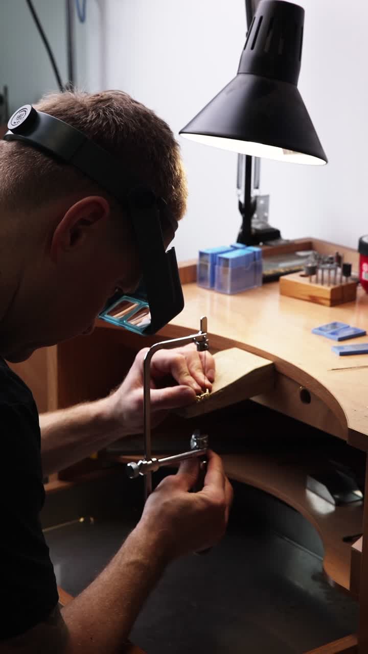 Jeweler Sawing Metal Piece with Precision at Workbench