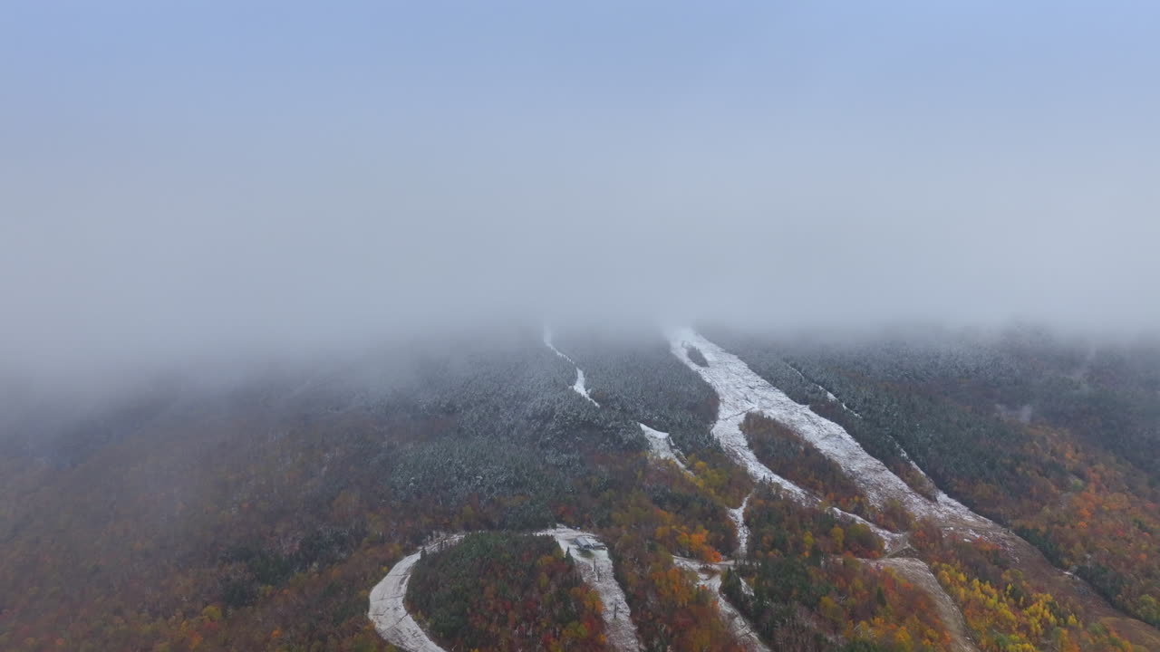 Slope of the mountain hidden by the thick mist. Change of the autumn into winter season. Aerial view.