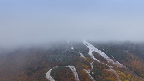 slope of the mountain hidden by the thick mist. change of the autumn into winter season. aerial view.