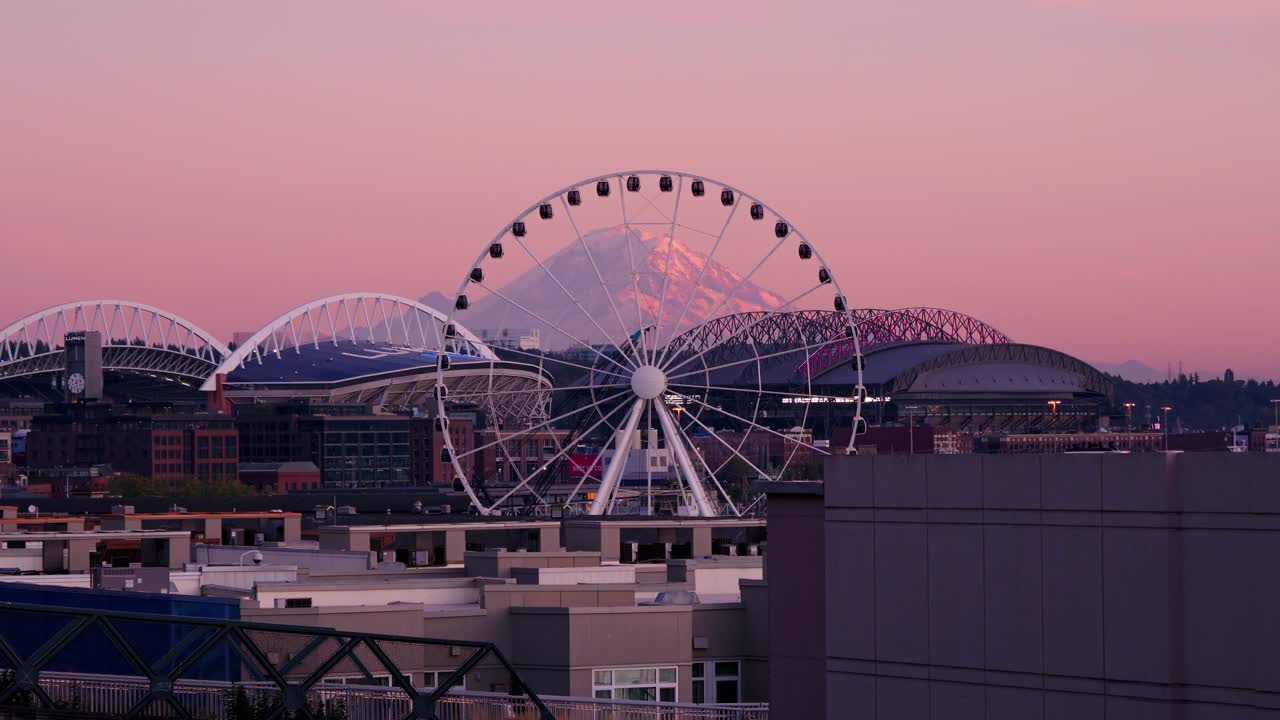 The Seattle Great Wheel moving on a during a summer sunset with Mount Rainier in the background.