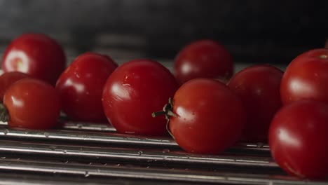 Tomates-Rojos-Maduros,-Recién-Lavados-Cayendo-Sobre-Un-Secador-De-Metal-En-Primer-Plano