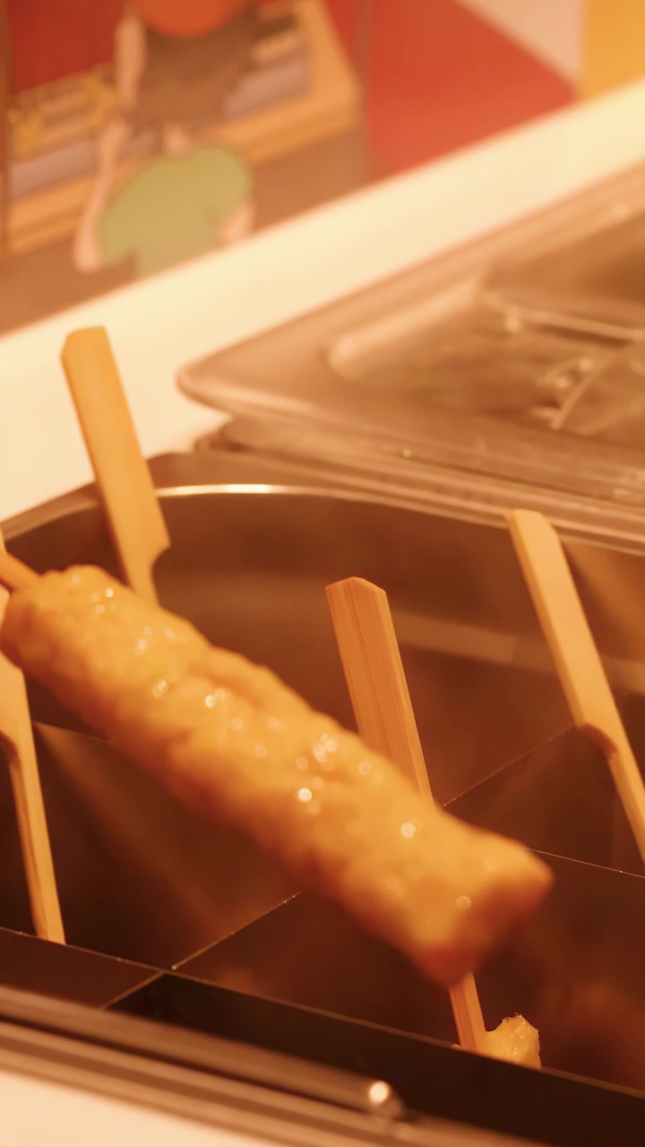 Primo piano di una donna che prende spiedini di oden fumanti da un bancone di street food