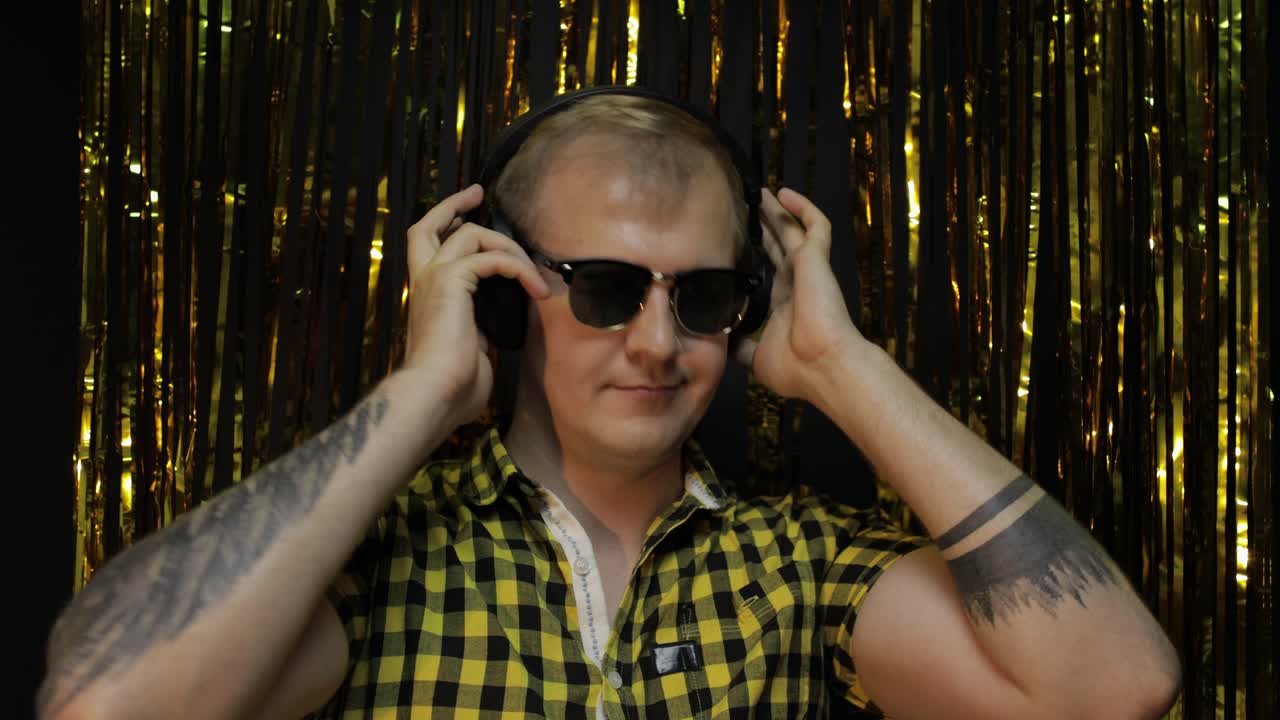 retrato de un hombre caucásico bailando sobre un fondo negro. tiras de papel de aluminio doradas brillantes. fiesta, música, discoteca