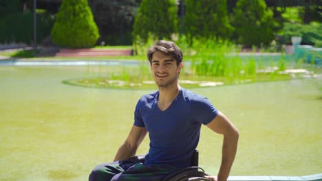 young disabled man in wheelchair smiling looking at camera outdoors.