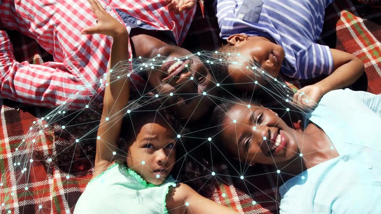 Family lying on red-white plaid blanket, cam starting and casting pulsing tech mesh over heads