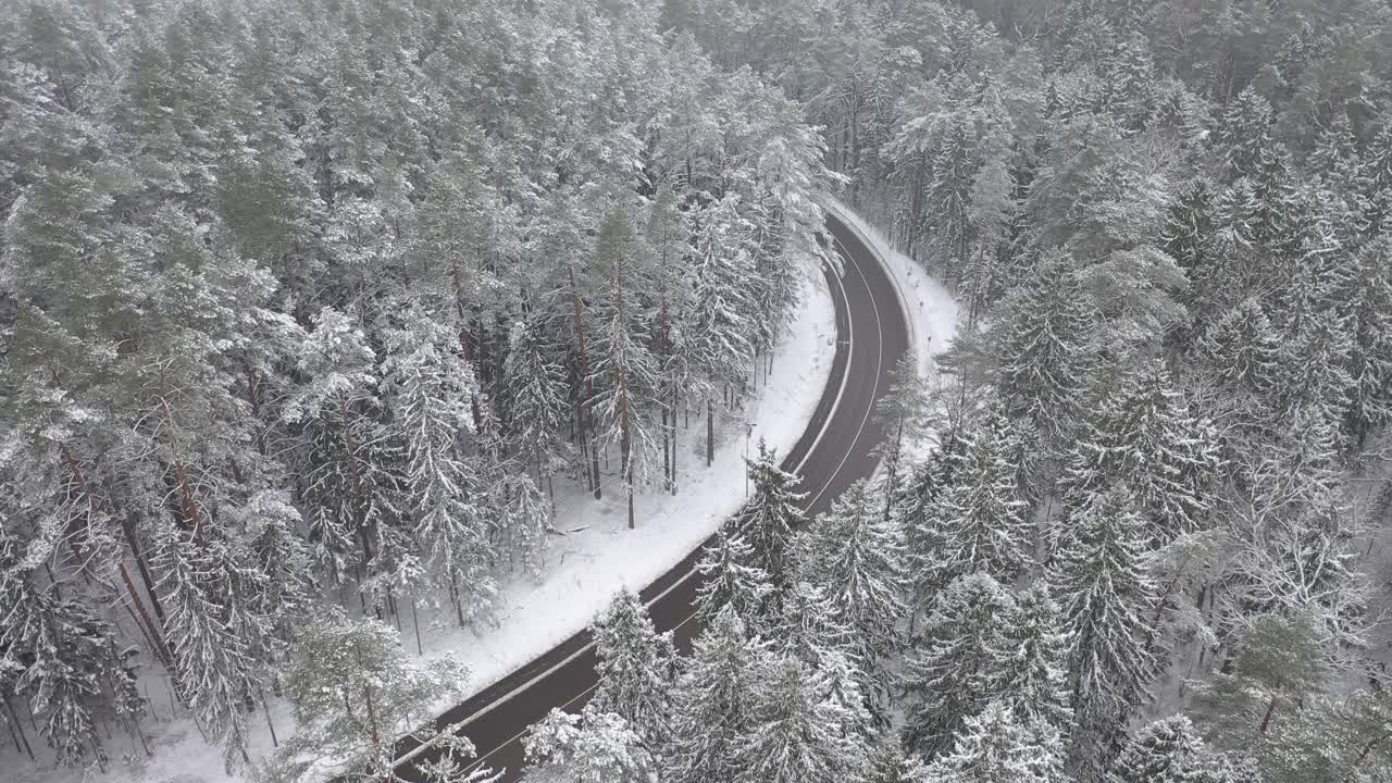 리투아니아 카우나스 카운티의 눈 덮인 숲과 시골 도로의 드론 조감도
