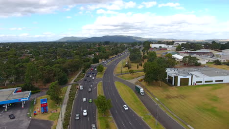 Flying-over-main-road,-hills-in-background