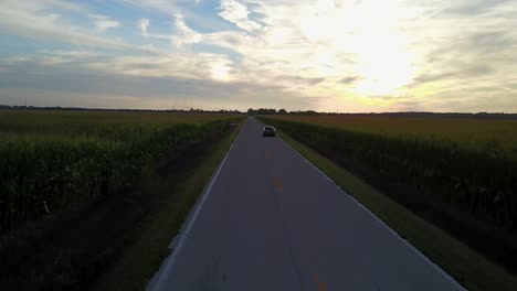 Car-Driving-On-Country-Road-Sunset-Drone-Chase-Footage