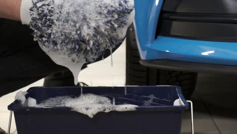 washing a blue car with a wash mitt and soap