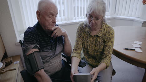 elderly couple using blood pressure monitor at home