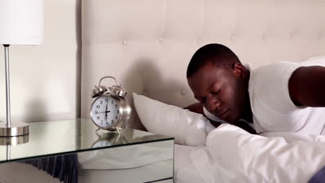 man waking up and turning off his alarm clock