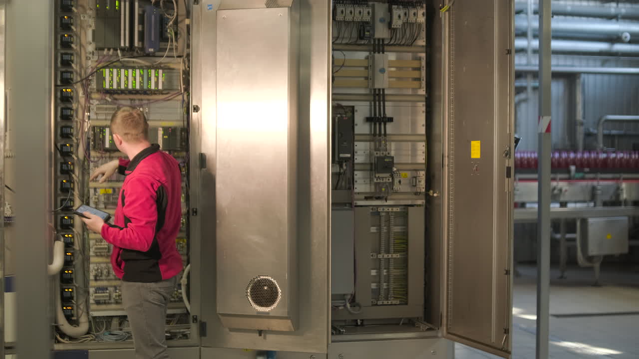 Engineer Inspecting Industrial Control Panel with Tablet in Factory