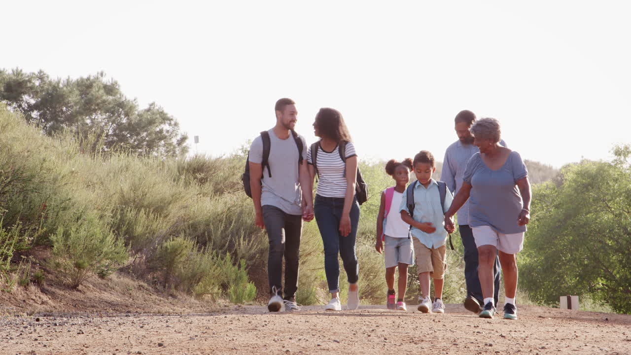 familia de varias generaciones con mochilas caminando juntos por el campo