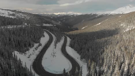 Vehicles-drive-carefully-on-icy-mountain-pass-highway-switchback