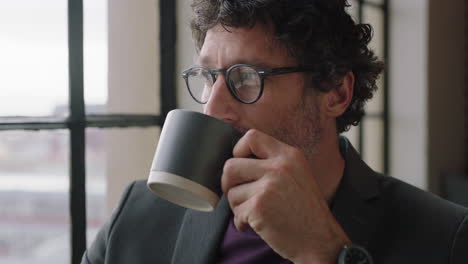 portrait happy mature business man drinking coffee at home enjoying relaxed morning looking out window planning ahead thinking successful caucasian male smiling wearing glasses in apartment loft