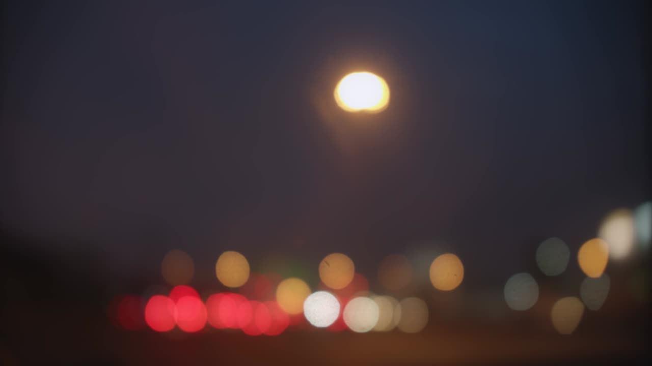 Kaunis värikäs kimalteleva bokeh loistaa auton valoista sumealla yötaustalla, ruuhka kaupungin kadulla
