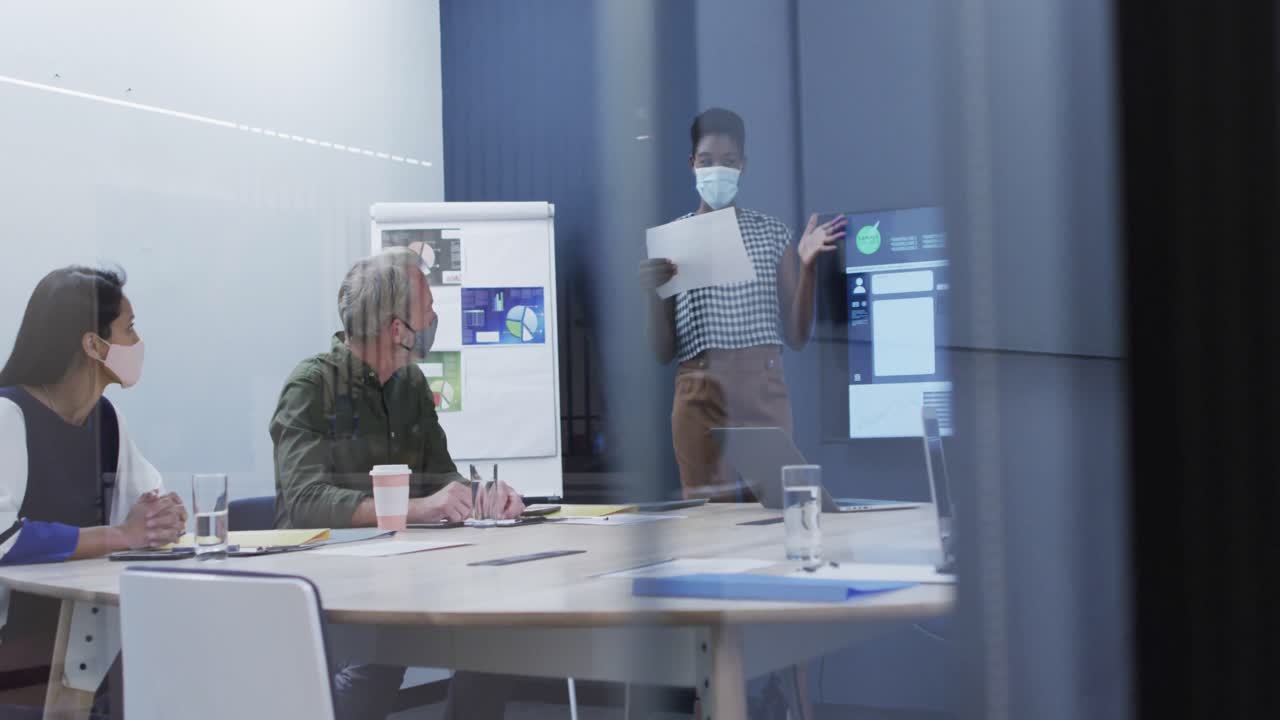 diversas personas de negocios con máscaras faciales sentadas escuchando la presentación en la sala de reuniones