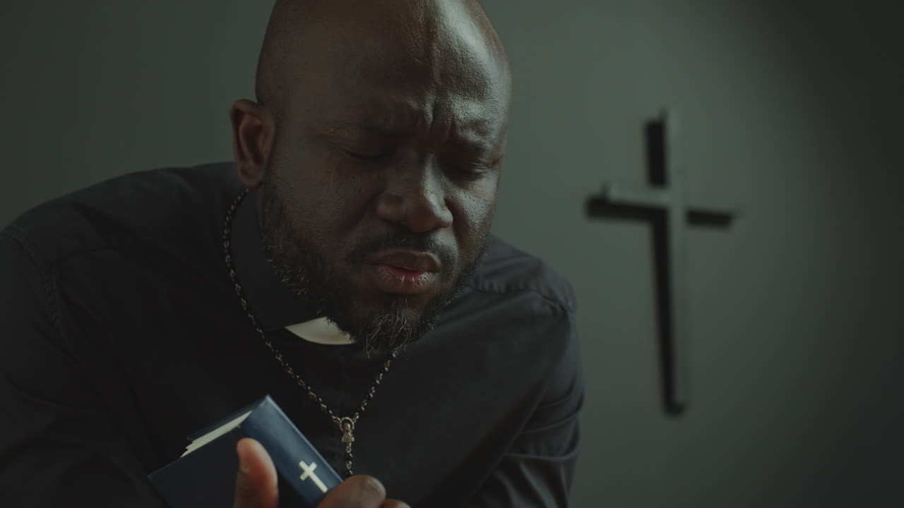 African American Catholic Priest Holding Bible and Praying in Shrine