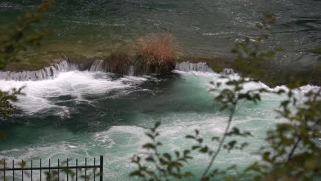 Vista-De-Una-Cascada-Que-Fluye-Desde-Un-Estanque-Grande-A-Otro-Estanque-Azul-En-El-Parque-Nacional-Krka-En-Croacia-A-¼-De-Velocidad