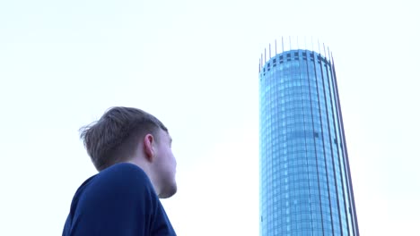 man looking up at a tall skyscraper