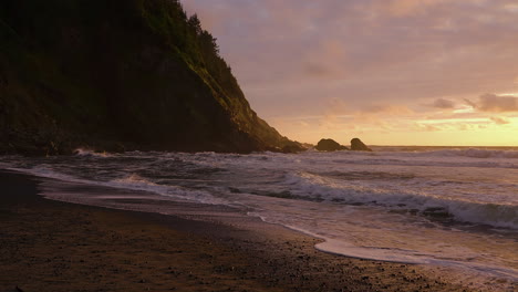 waves washing up pebble shore of tropical beach during sunset