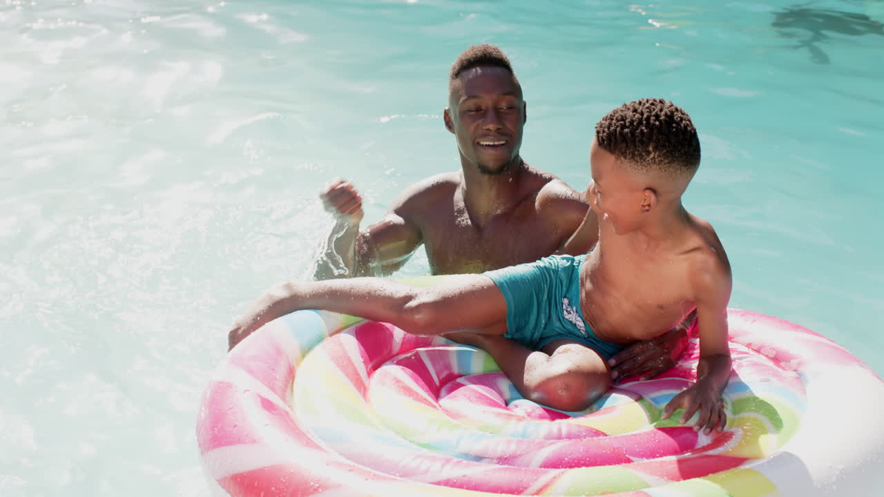 Father and son playing in pool with inflatable float, enjoying summer day