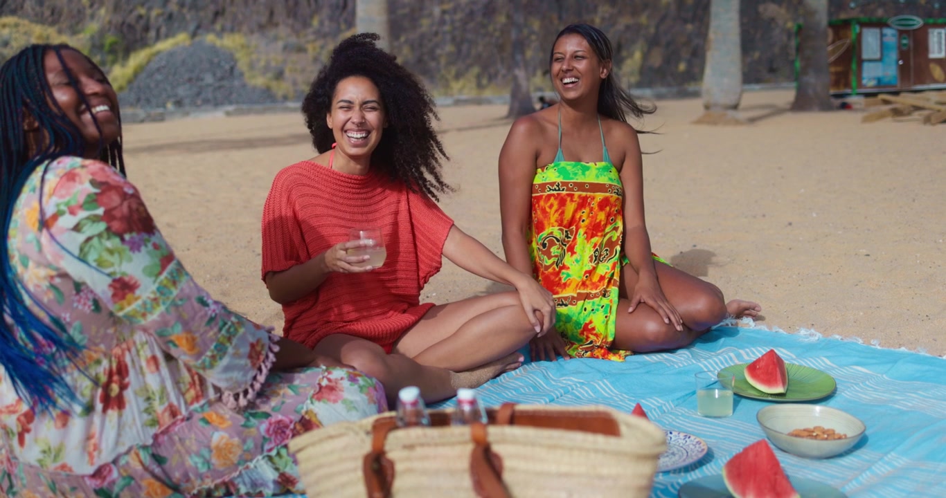 Giovani amiche felici che fanno un picnic in spiaggia
