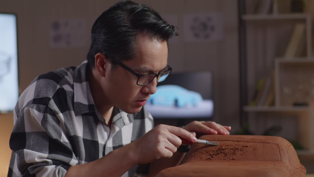 primer plano de un hombre asiático diseñador de automóviles celebrando el éxito trabajando en la escultura de arcilla de automóviles por rastrillo o alambre en el estudio