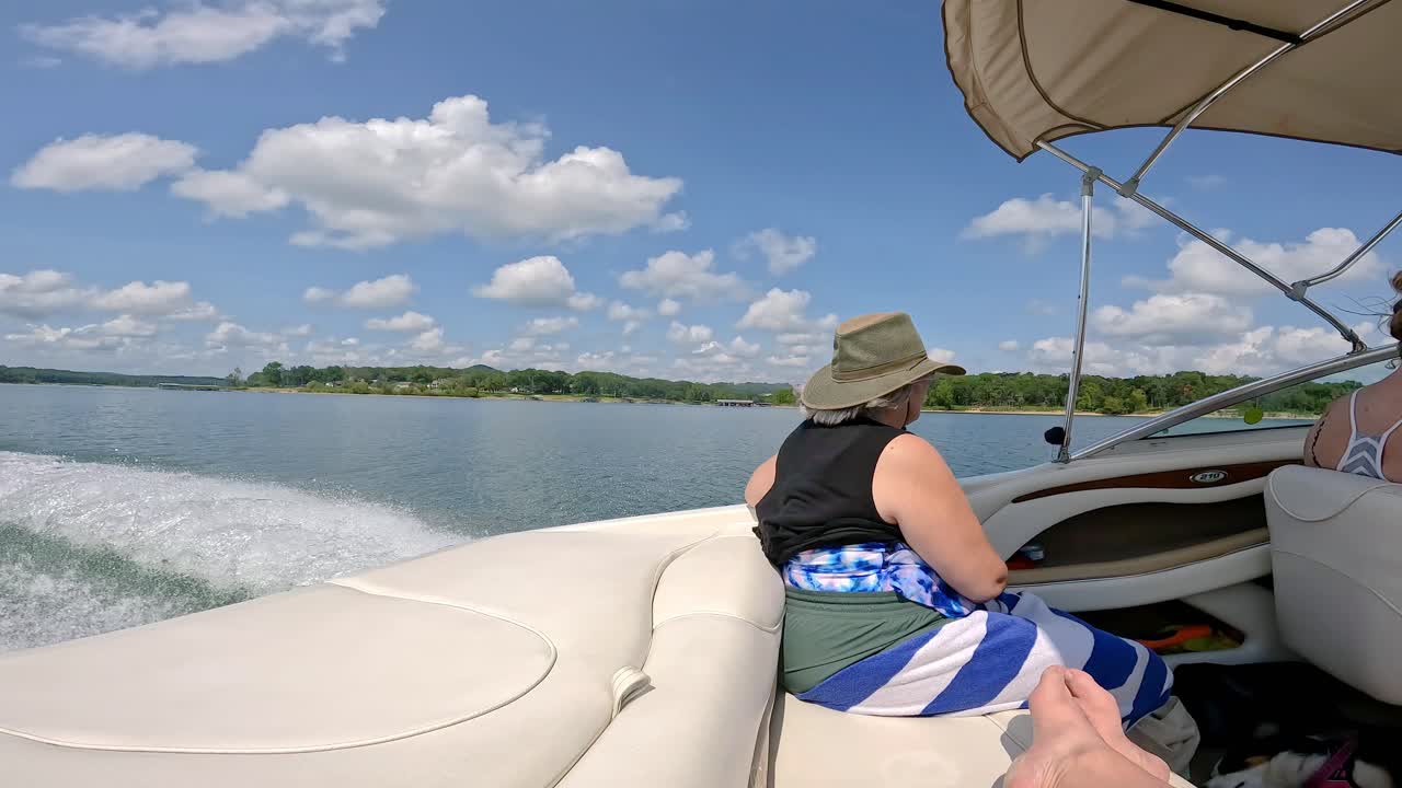 cámara lenta de la mujer viendo pasar el paisaje del lago table rock en missouri usa mientras se sienta en la parte trasera del barco deportivo en una tarde soleada