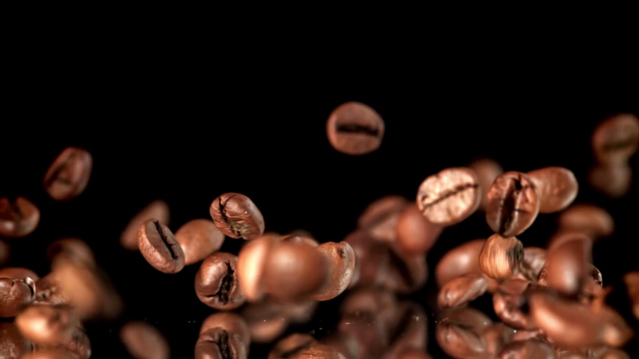 Chicchi di caffè tostati che cadono al rallentatore su sfondo nero