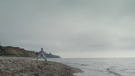 man training martial technique on seacoast. athletic fighter practicing karate.
