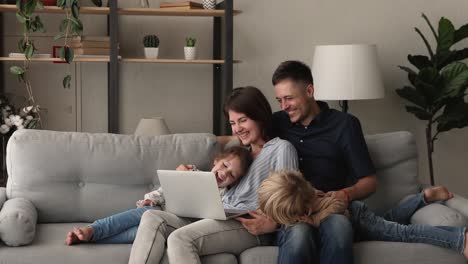 pareja y niños en edad preescolar viendo una película familiar en la computadora portátil