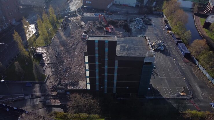 Demolizione di parcheggio multipiano in calcestruzzo, scavo di cantiere per la riqualificazione urbana, ripresa aerea.